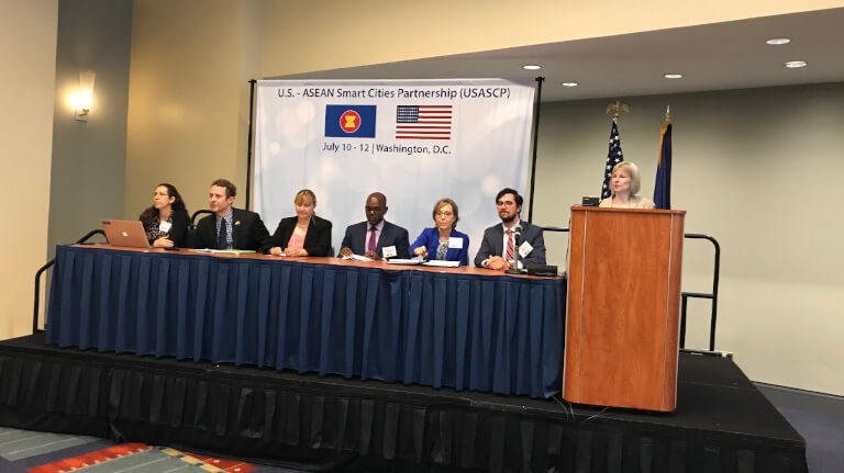 Group of men and woman sitting on a stage answering questions asked by audience 
