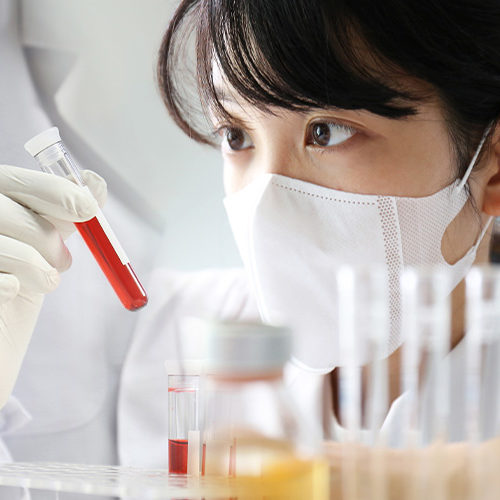 Woman in a lab examining a liquid in a test tube